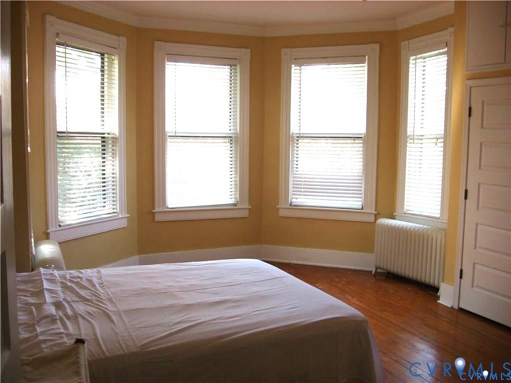243 South Adams Street Petersburg, VA 23803 - Photo 5 of 8 a bedroom with a bed and wooden floor