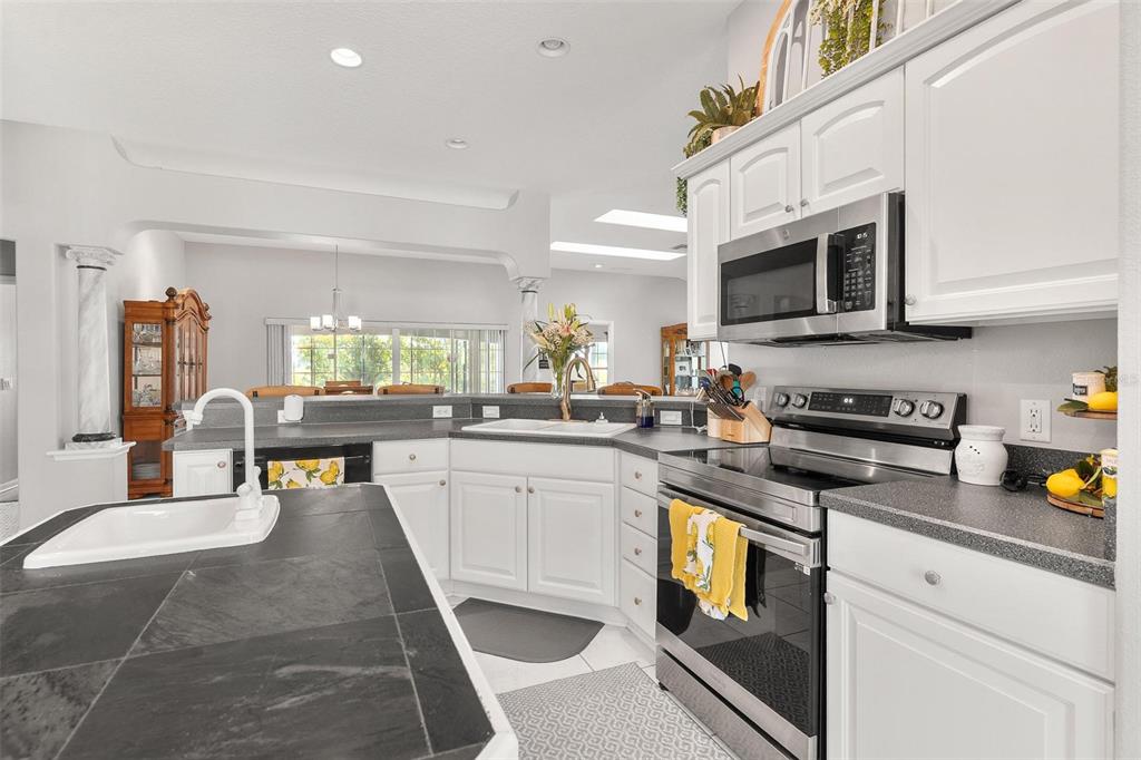 1027 Urico Road Lady Lake, FL 32159 - Photo 15 of 49 a kitchen with stainless steel appliances granite countertop a stove a sink dishwasher and a microwave oven with white cabinets