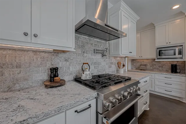 a kitchen with stainless steel appliances granite countertop white cabinets stove top oven and sink