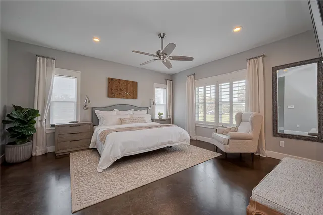 a spacious bedroom with a bed couch and windows