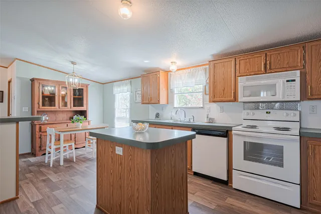 a kitchen with granite countertop a refrigerator a sink a stove and wooden floor