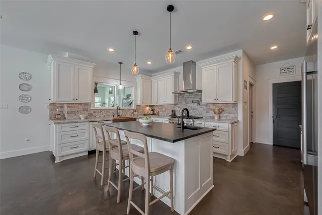 a kitchen with stainless steel appliances kitchen island granite countertop a refrigerator and white cabinets