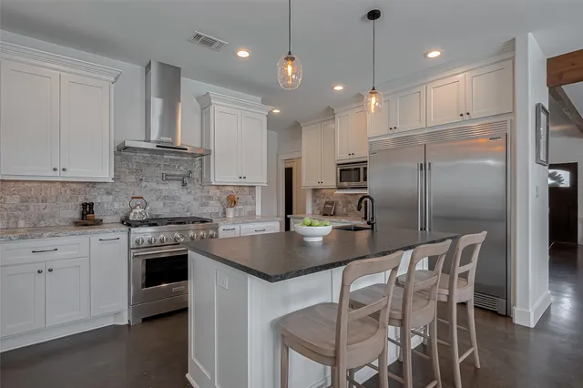 a kitchen with kitchen island a counter space a sink appliances and cabinets