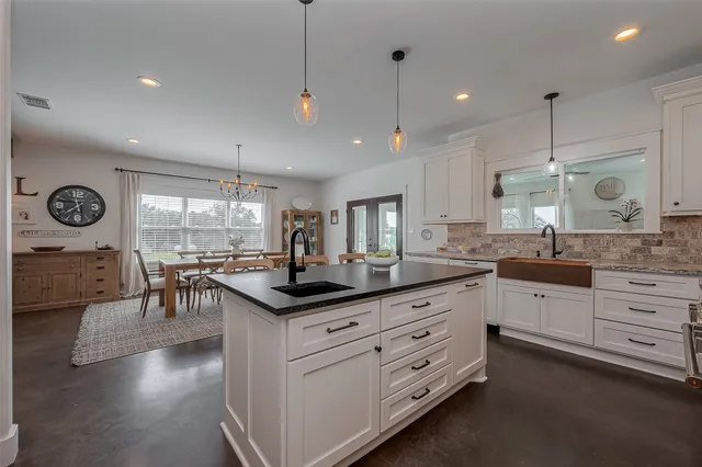 a kitchen with granite countertop a sink a stove cabinets and wooden floor