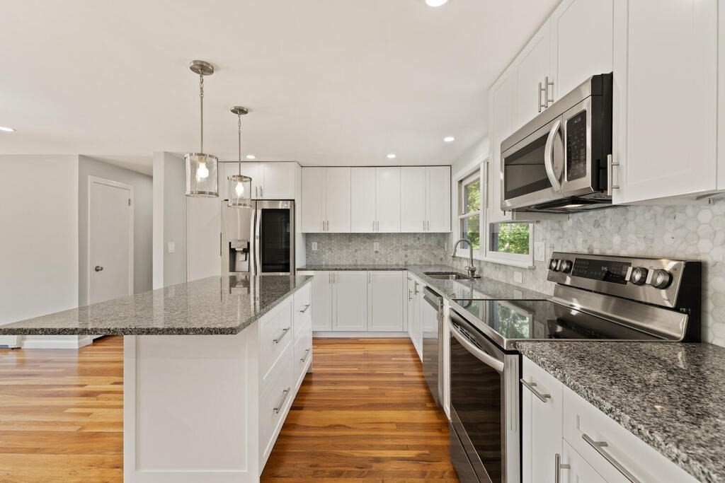 8 Smith Road Randolph, MA 02368 - Photo 5 of 31 a large kitchen with stainless steel appliances granite countertop a sink a stove and a wooden floors