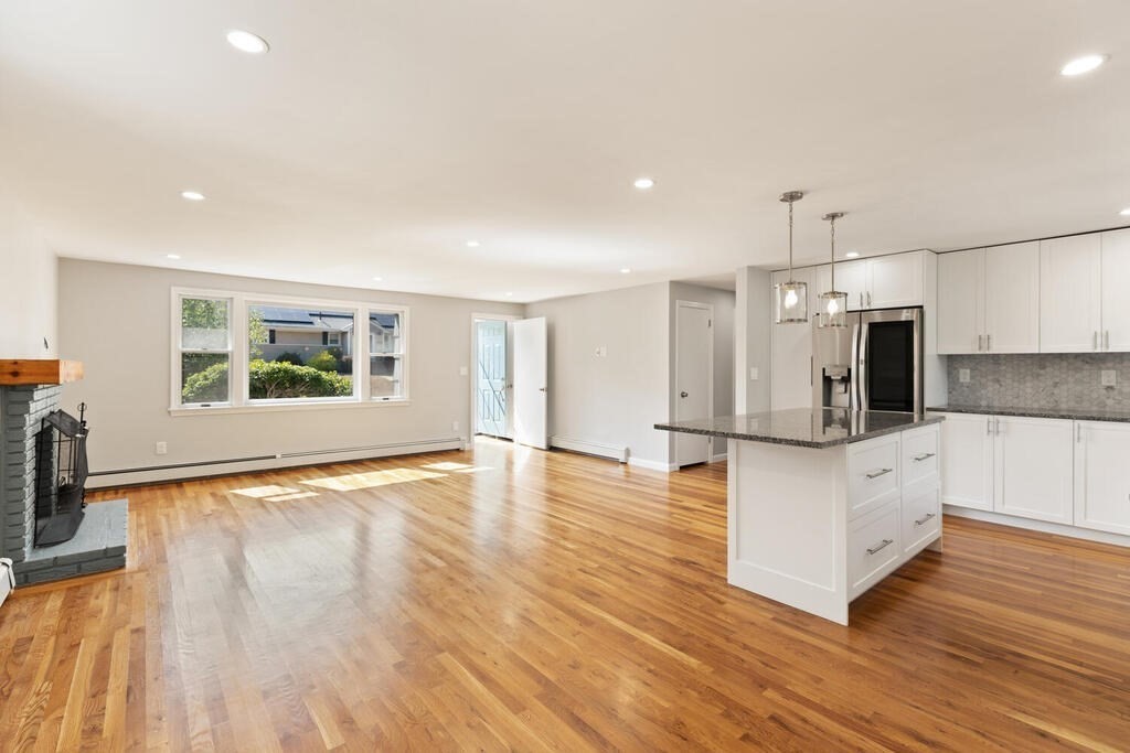 8 Smith Road Randolph, MA 02368 - Photo 9 of 31 a large white kitchen with kitchen island a sink wooden floor and a refrigerator