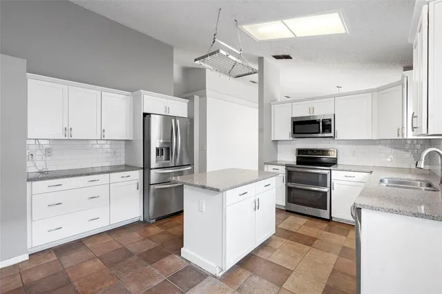 a kitchen with granite countertop white cabinets and stainless steel appliances