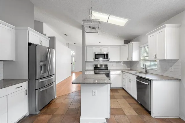 a kitchen with stainless steel appliances granite countertop a refrigerator a stove a sink dishwasher a refrigerator with white cabinets and wooden floor