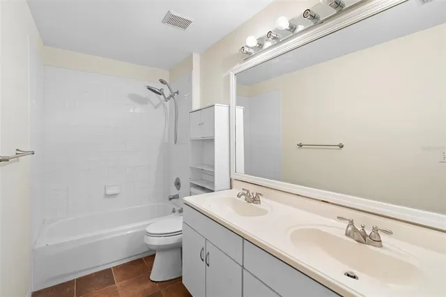 a bathroom with a double vanity sink toilet mirror and bathtub