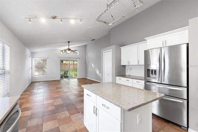 a kitchen with stainless steel appliances granite countertop a refrigerator a sink dishwasher a stove and white countertops with wooden floor