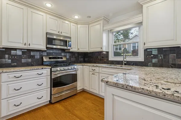 a kitchen with stainless steel appliances granite countertop a refrigerator a stove and a sink