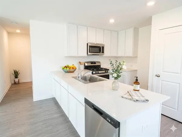 a kitchen with stainless steel appliances a sink a stove a refrigerator and white cabinets