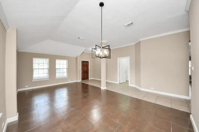 a view of a room with wooden floor chandelier and windows