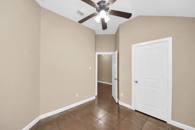 an empty room with closet and a chandelier fan