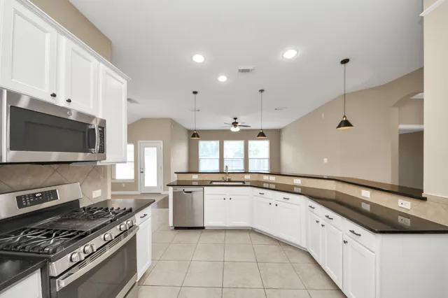 a large kitchen with stainless steel appliances granite countertop a stove and a sink