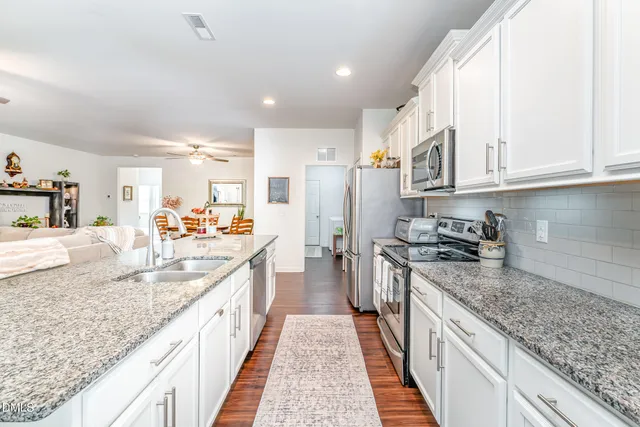 a large kitchen with stainless steel appliances granite countertop a lot of counter space and wooden floor
