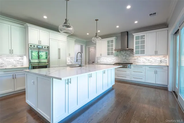 a kitchen with stainless steel appliances kitchen island granite countertop a sink a stove a refrigerator and island with wooden floor