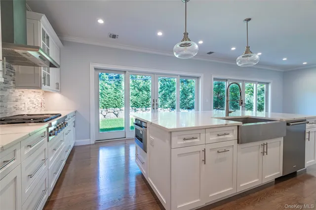 a kitchen with kitchen island granite countertop a stove a sink a center island and wooden floor