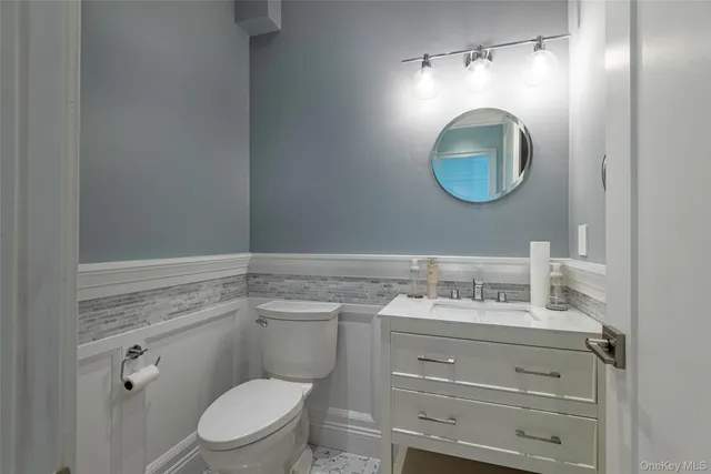 a bathroom with a toilet sink vanity and mirror