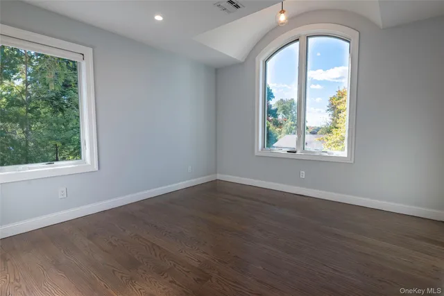an empty room with wooden floor windows and outdoor view