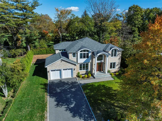 a front view of a house with garden and trees