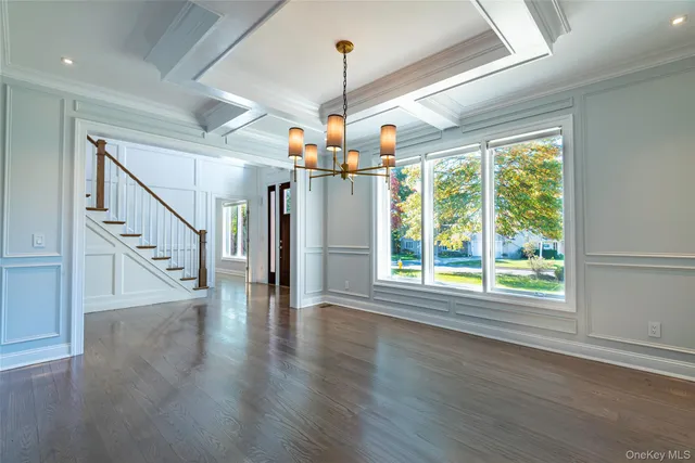 a view of a livingroom with wooden floor stairs and a chandelier