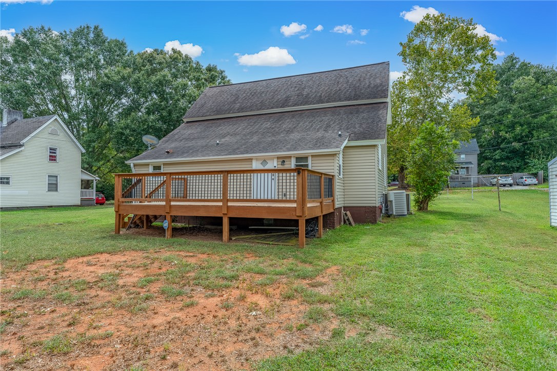 47 Square Street Pelzer, SC 29669 - Photo 5 of 29 An elevated wooden deck overlooks a grassy backyard surrounded by mature trees.