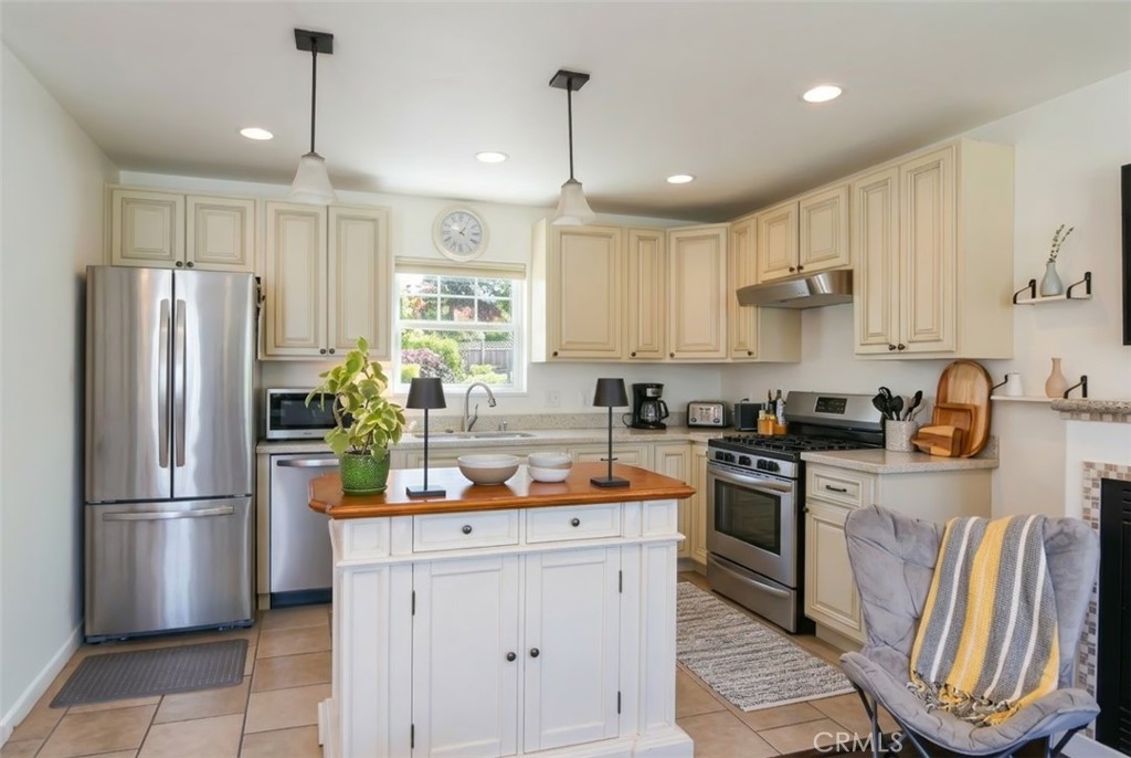 350 Java Street Morro Bay, CA 93442 - Photo 16 of 26 a kitchen with stainless steel appliances granite countertop a refrigerator a sink dishwasher a stove a dining table and chairs with wooden floor