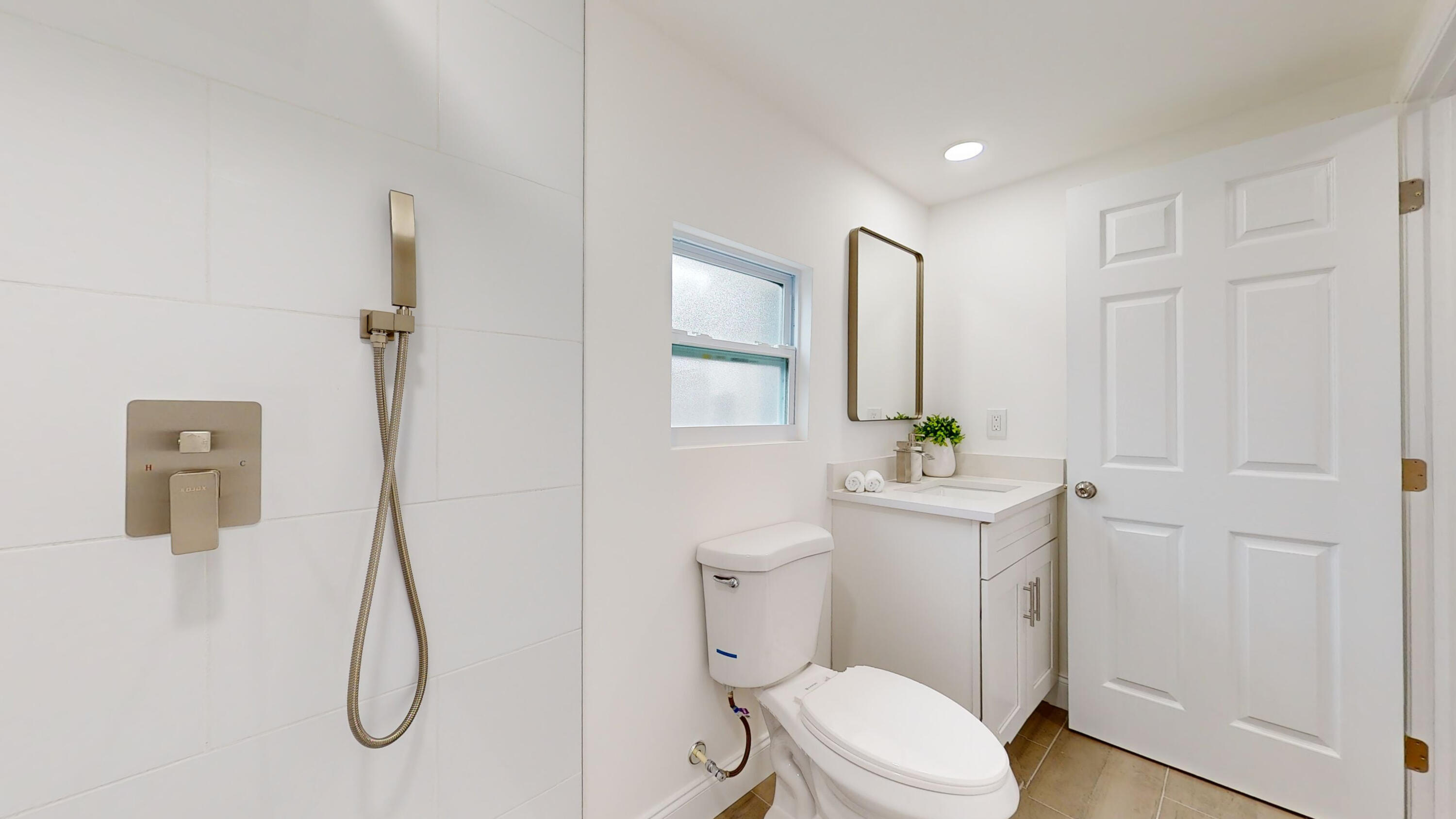 6674 4th Street Jupiter, FL 33458 - Photo 14 of 21 a bathroom with a toilet sink vanity and shower