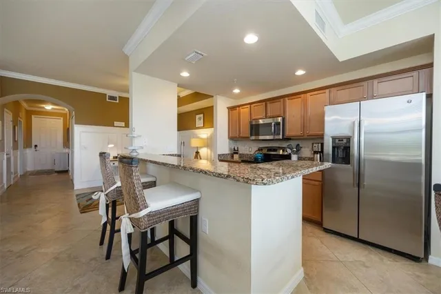 a kitchen with stainless steel appliances granite countertop a refrigerator a stove a sink a dining table and chairs