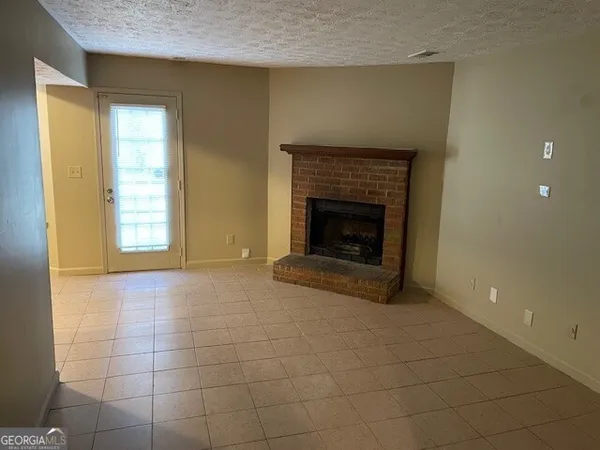 a view of an empty room with a fireplace and a window