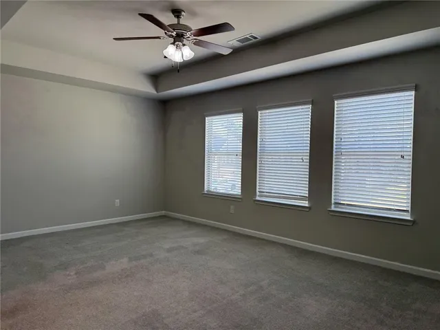 an empty room with windows and fan