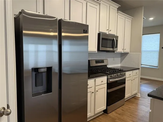 a kitchen with stainless steel appliances granite countertop a stove a refrigerator and a microwave