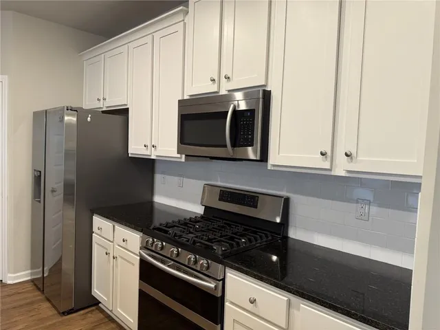 a kitchen with stainless steel appliances granite countertop white cabinets and refrigerator