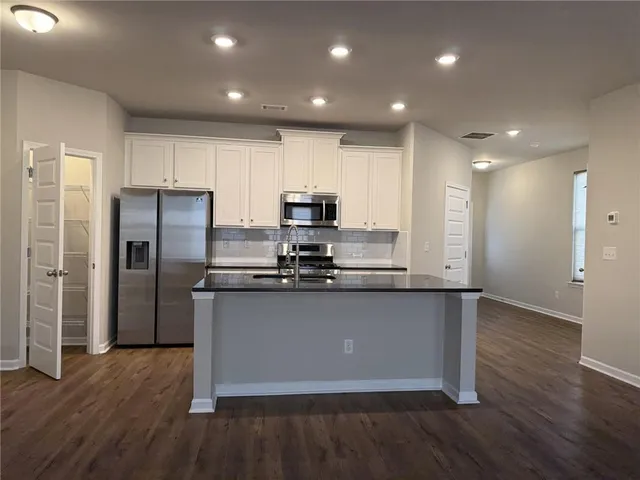 a kitchen with stainless steel appliances granite countertop a refrigerator a sink a stove a microwave and wooden floor