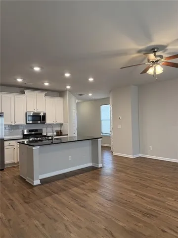 a kitchen with stainless steel appliances kitchen island granite countertop a stove a sink and a refrigerator