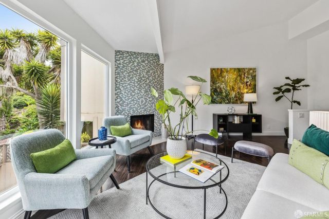 a living room with furniture potted plant floor and a large window