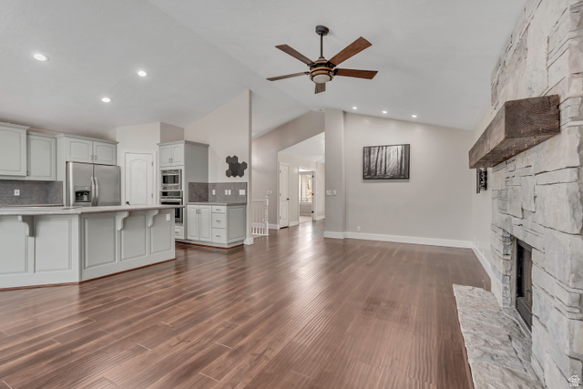 2154 Wasatch Boulevard Sandy, UT 84092 - Photo 27 of 55 Unfurnished living room featuring vaulted ceiling, a ceiling fan, a fireplace, dark wood finished floors, and recessed lighting