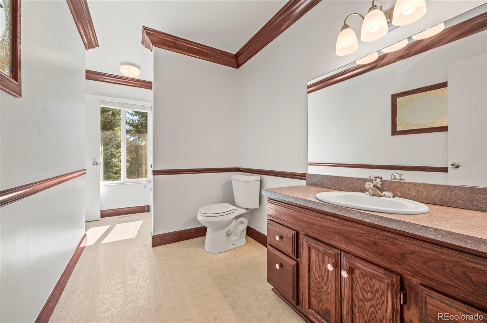 4420 South Vivian Way Morrison, CO 80465 - Photo 19 of 50 a bathroom with a granite countertop sink a large mirror and a toilet