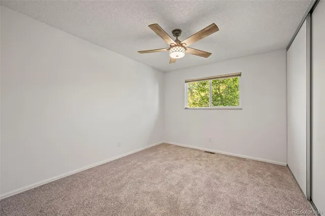 an empty room with windows and fan
