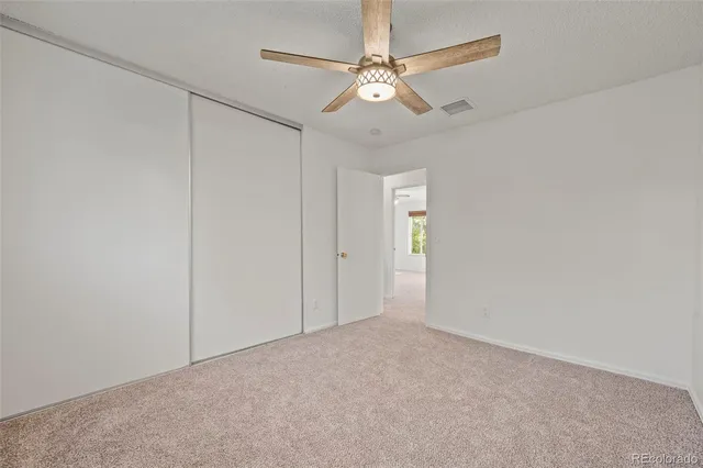 a view of an empty room with a chandelier fan