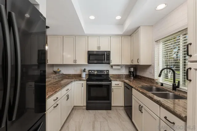a kitchen with granite countertop white cabinets and stainless steel appliances