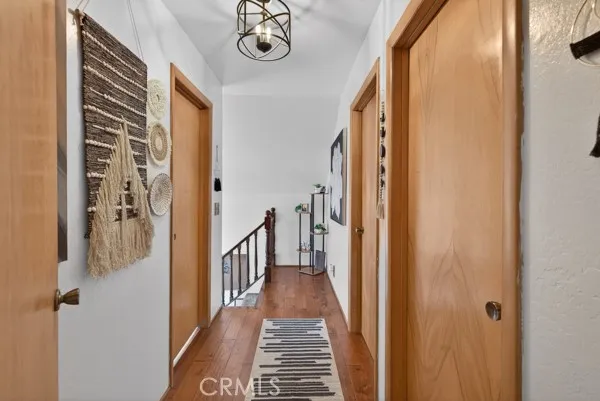 a view of a hallway with wooden floor and a bathroom