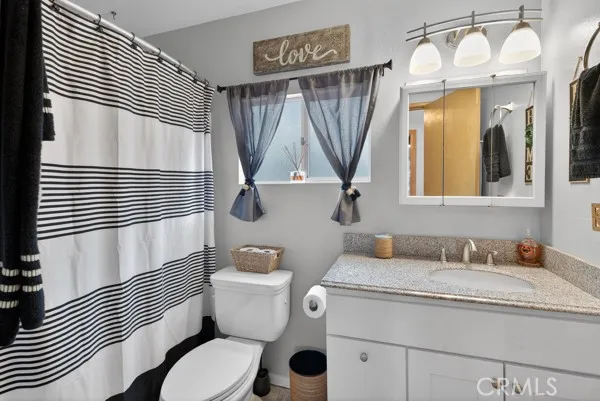 a bathroom with a granite countertop toilet sink and mirror