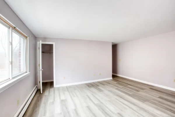a view of an empty room with closet and a window