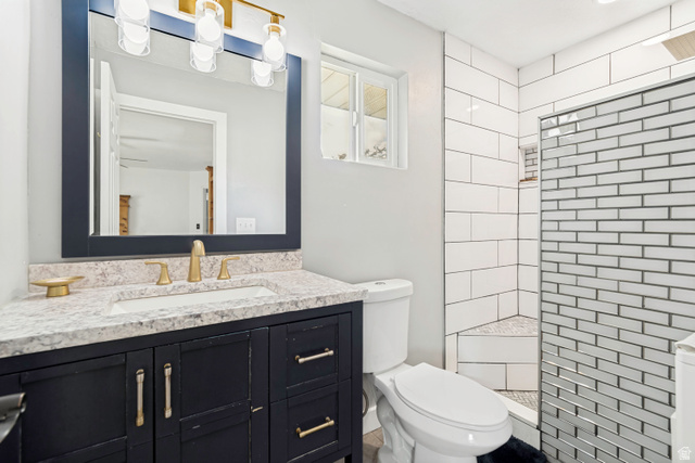 332 East Magellan Lane Elk Ridge, UT 84651 - Photo 10 of 24 Bathroom featuring a dark wood-finish vanity with a light speckled countertop, an undermount sink, and brass-finish fixtures