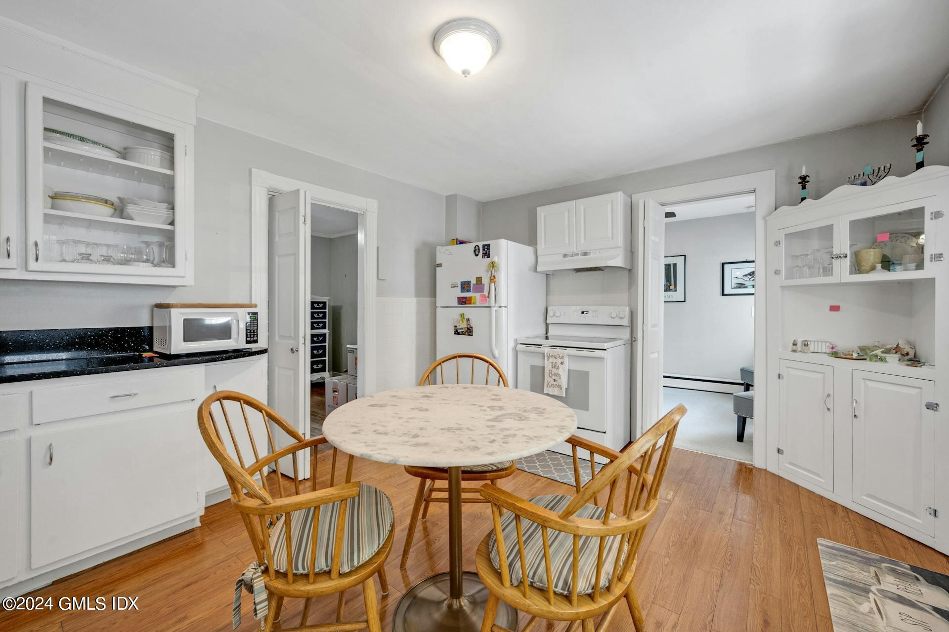 334 Palmer Hill Road Riverside, CT 06878 - Photo 3 of 19 a kitchen with stainless steel appliances granite countertop a dining table and chairs a refrigerator with wooden floors