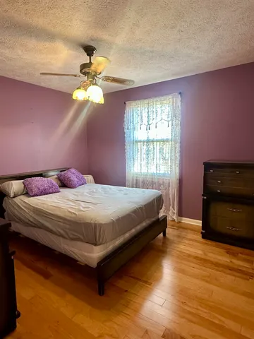 a bedroom with a bed and a dresser with wooden floor