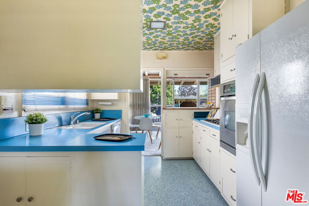 11368 Berwick Street Los Angeles, CA 90049 - Photo 10 of 31 a kitchen with stainless steel appliances a refrigerator a sink a stove and white cabinets
