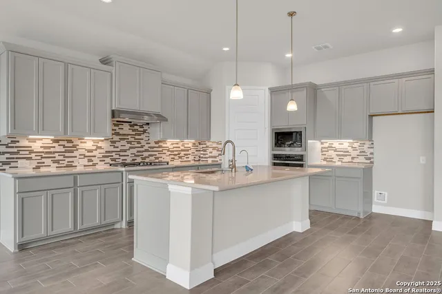 a kitchen with kitchen island granite countertop a sink stainless steel appliances and white cabinets